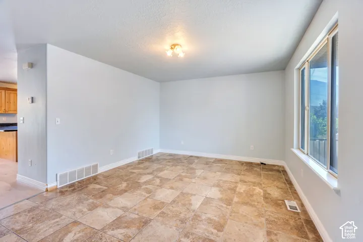 Spacious interior room featuring tile flooring, light neutral wall paint, and white baseboards