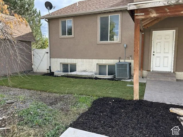 Exterior featuring a stucco facade, concrete foundation, white six-panel door, covered porch, and ground-level window wells