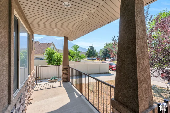 Covered porch featuring a concrete surface, black metal railing, and recessed lighting