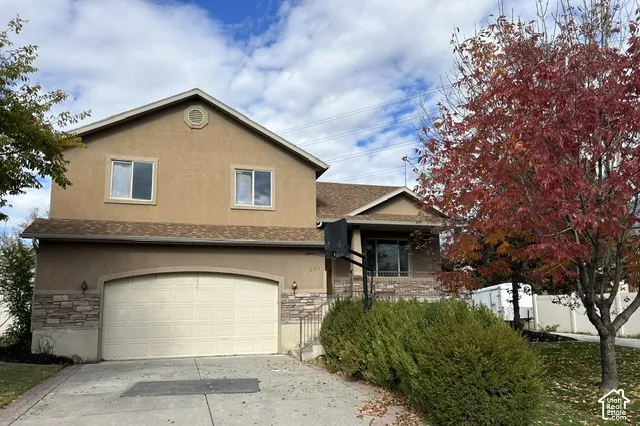 Two-story residence featuring a stucco exterior, stone veneer accents, an attached two-car garage, and an asphalt shingle roof