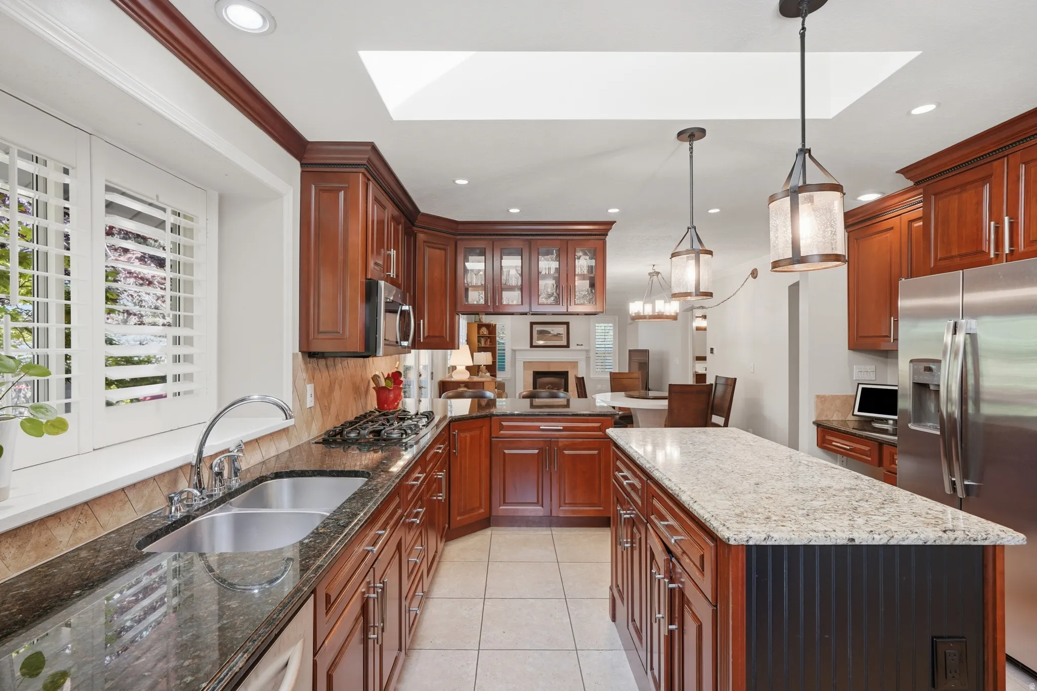 Kitchen featuring wood cabinetry, granite countertops, a central island, recessed lighting, and a skylight
