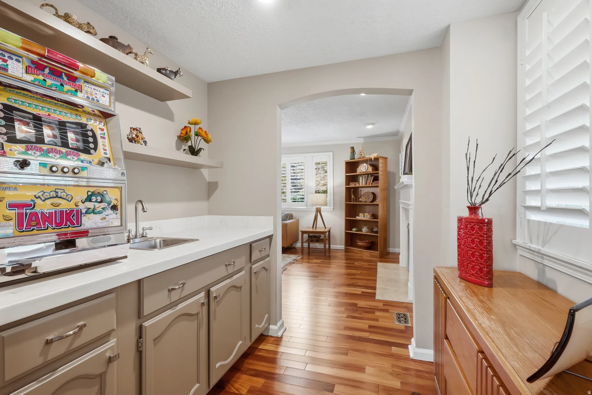 Wet bar featuring light-toned cabinetry, a stainless steel sink, and light countertops