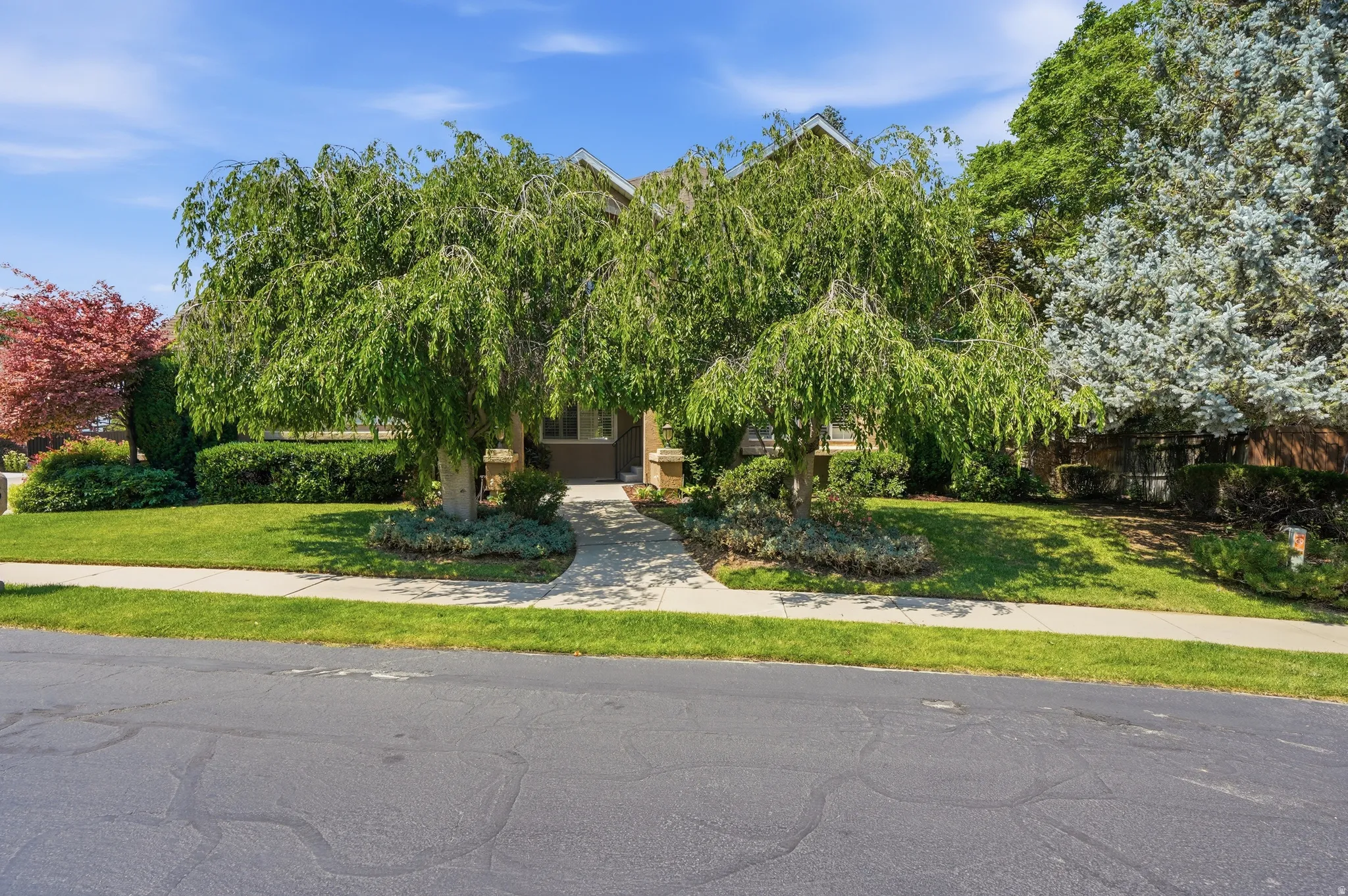 Front exterior featuring two weeping willow trees