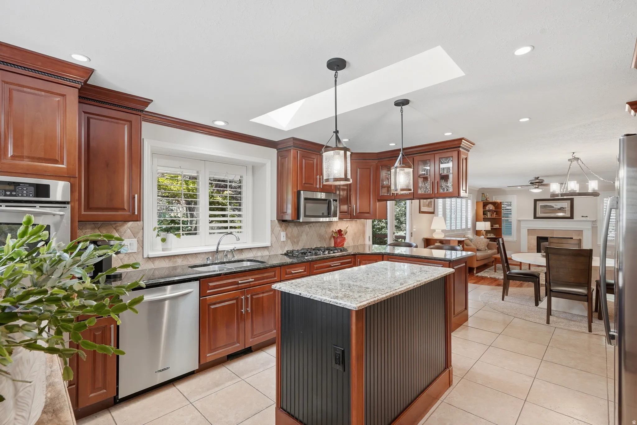 Kitchen featuring stainless steel appliances, double oven, granite countertops, and a central island with a beadboard base