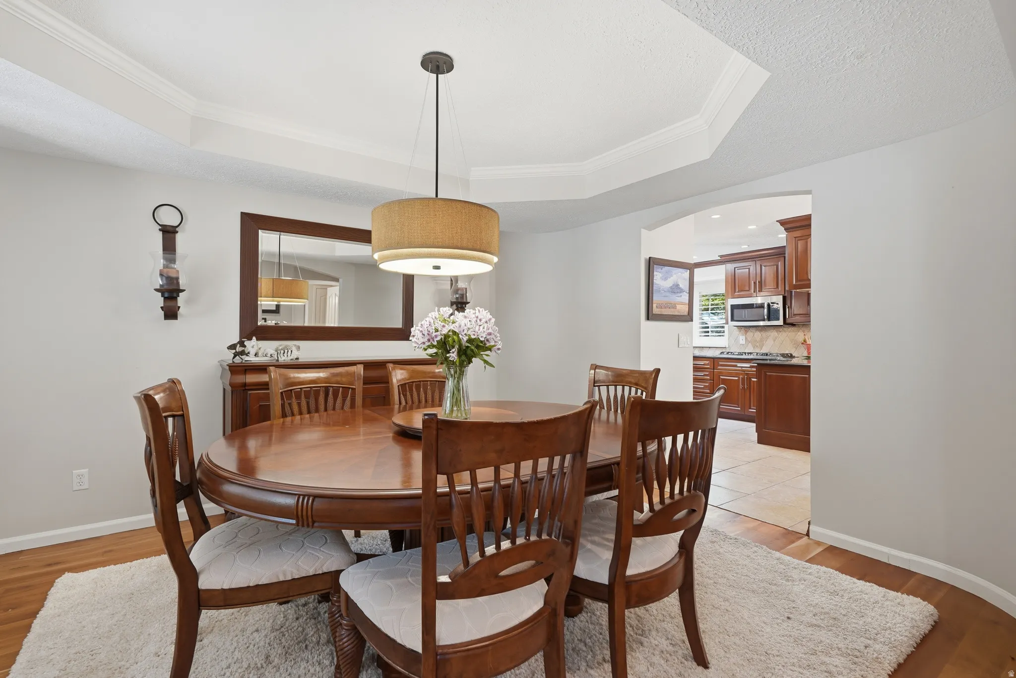 Formal dining area featuring a tray ceiling, wood-finish flooring, and an arched entryway
