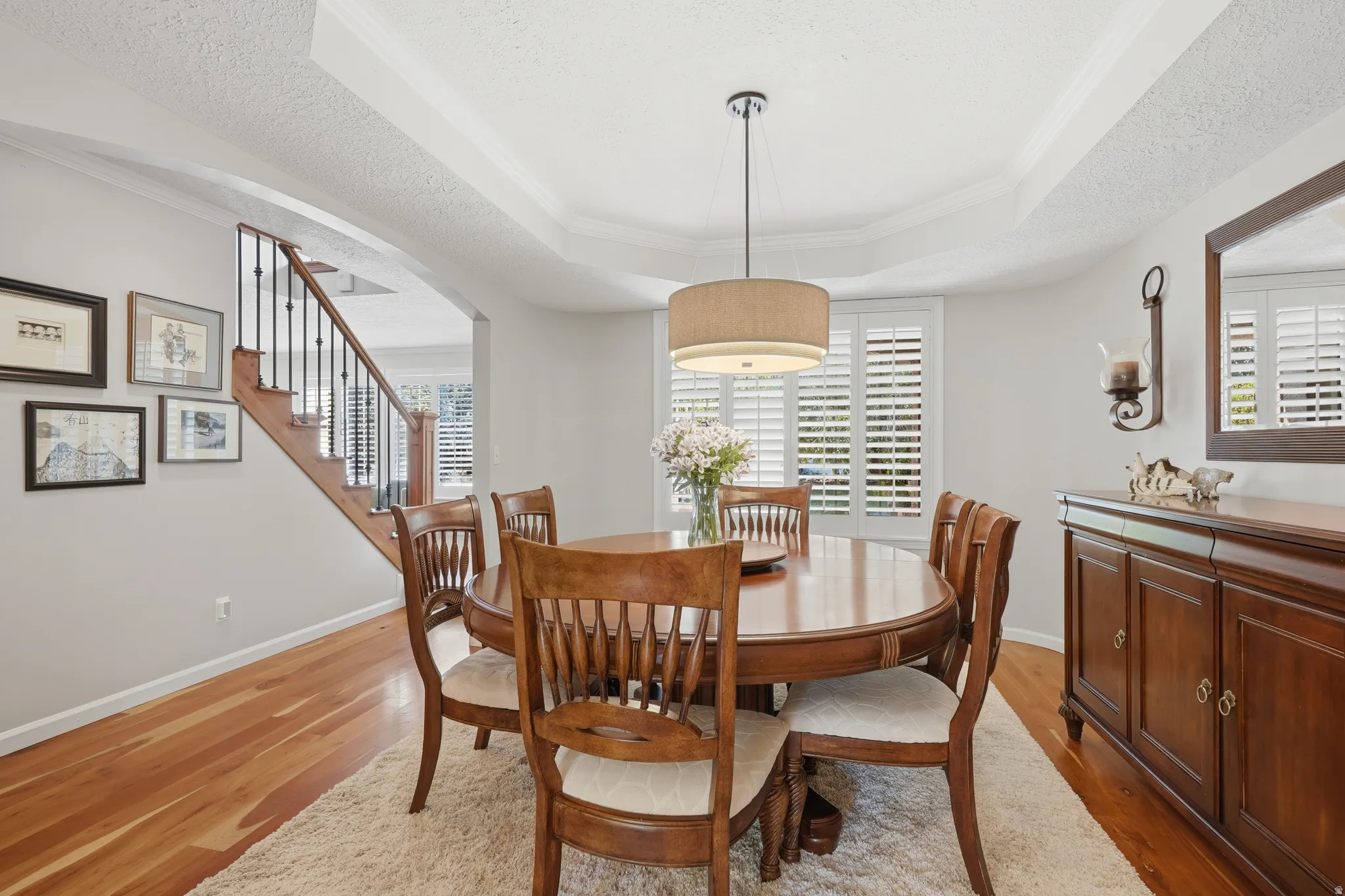 Formal dining area featuring hardwood flooring, a coffered ceiling, and a drum pendant light fixture