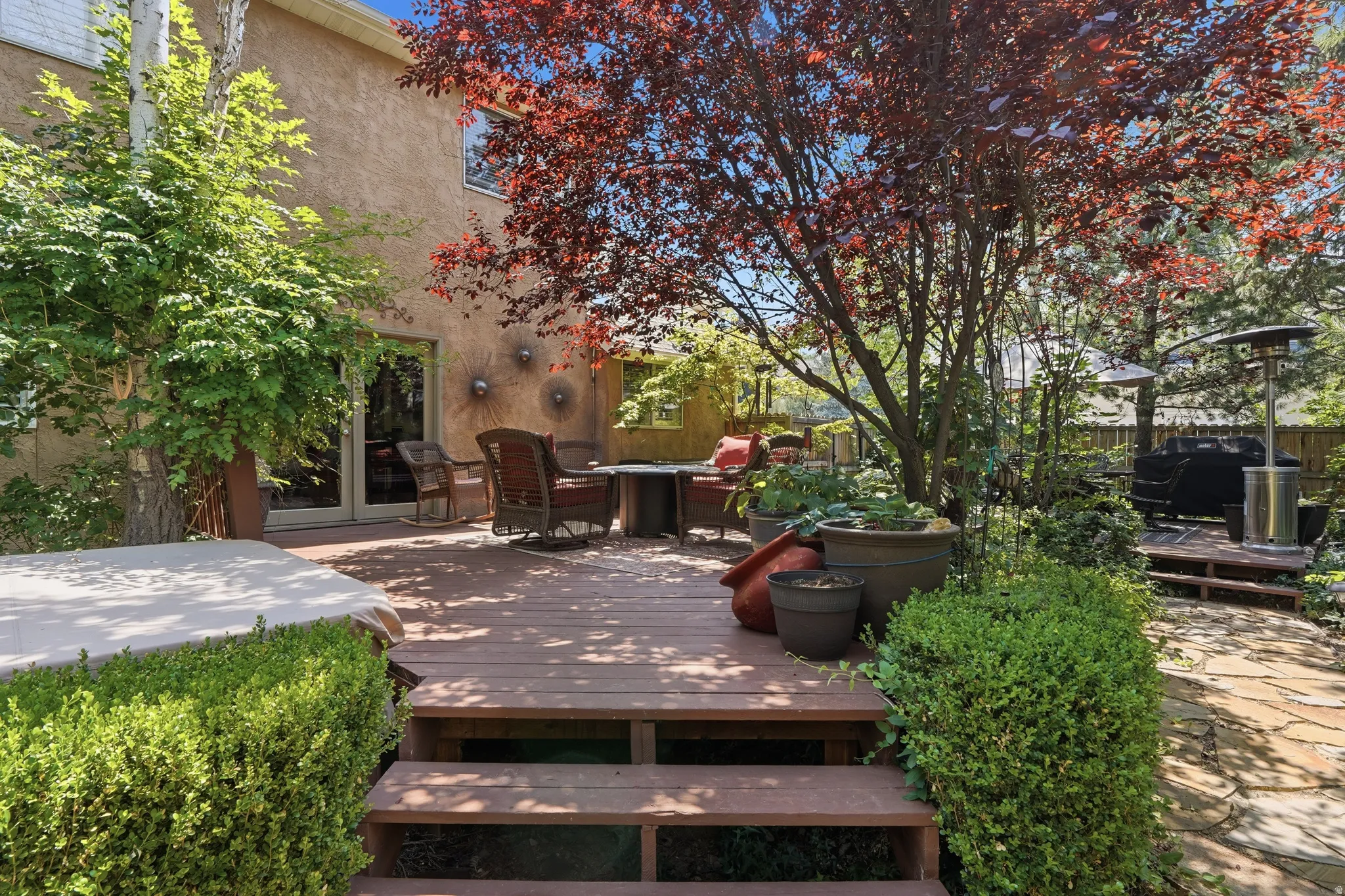 Multi-level wood deck featuring mature landscaping, and stone paver patio elements