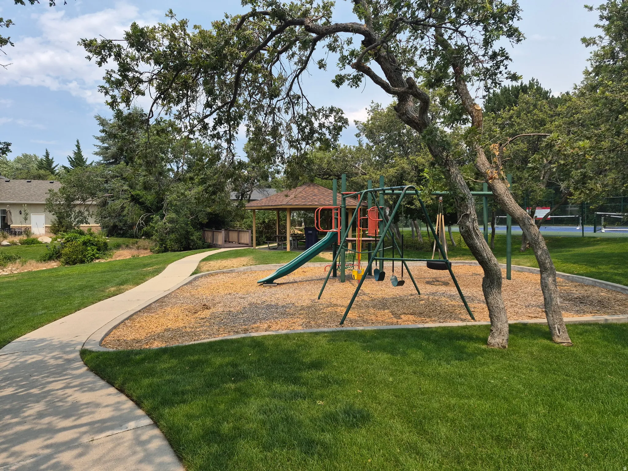Community playground featuring a slide, swings, and a shaded picnic area