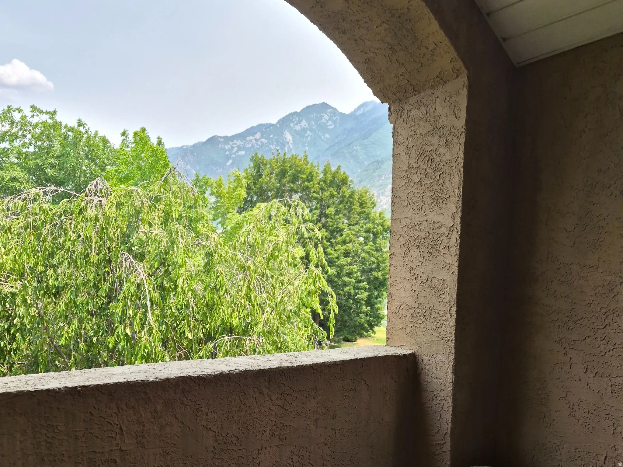 Covered balcony featuring textured stucco walls and arched ceiling detail
