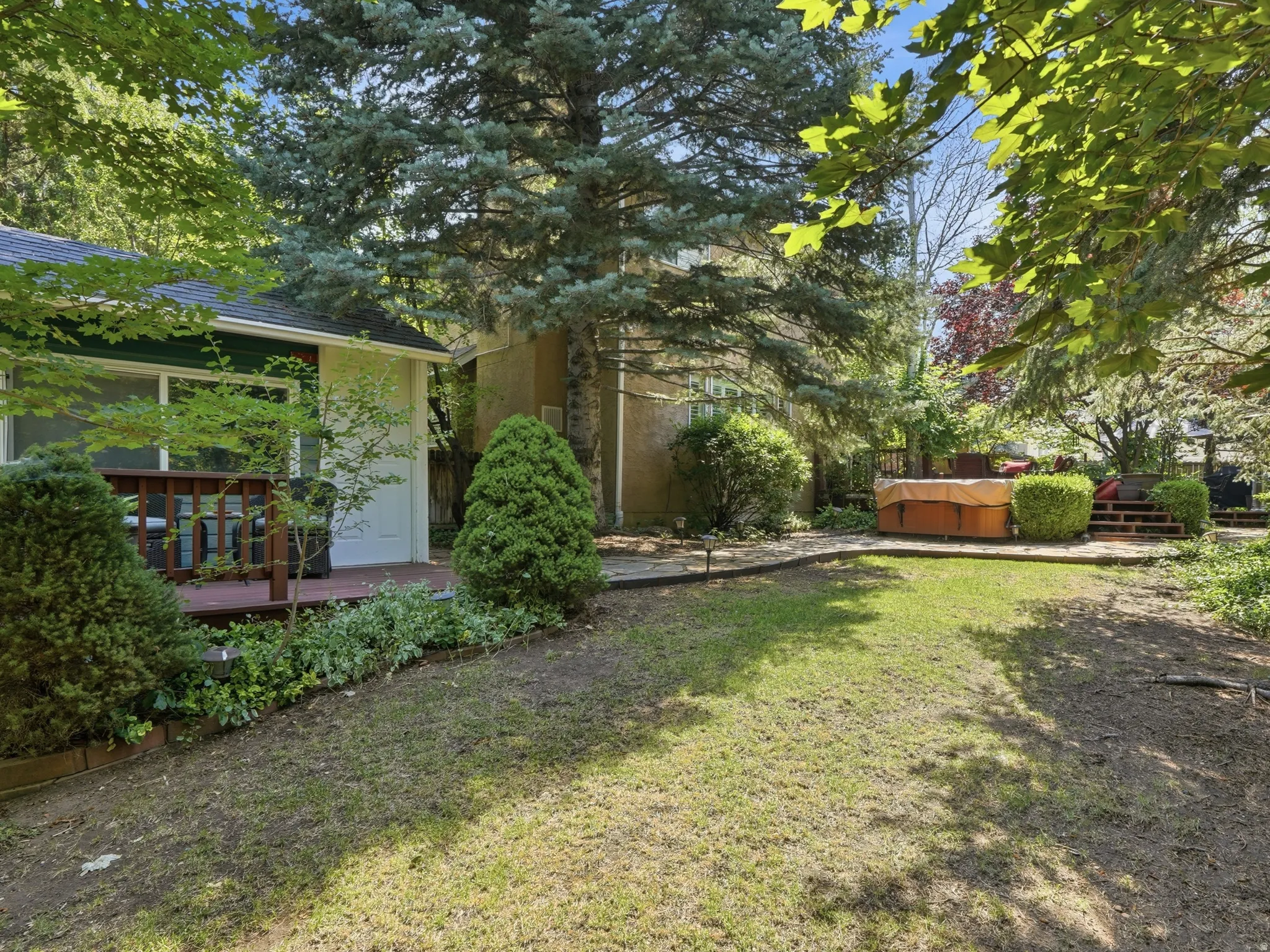 Spacious backyard featuring mature trees, and a private deck with a hot tub