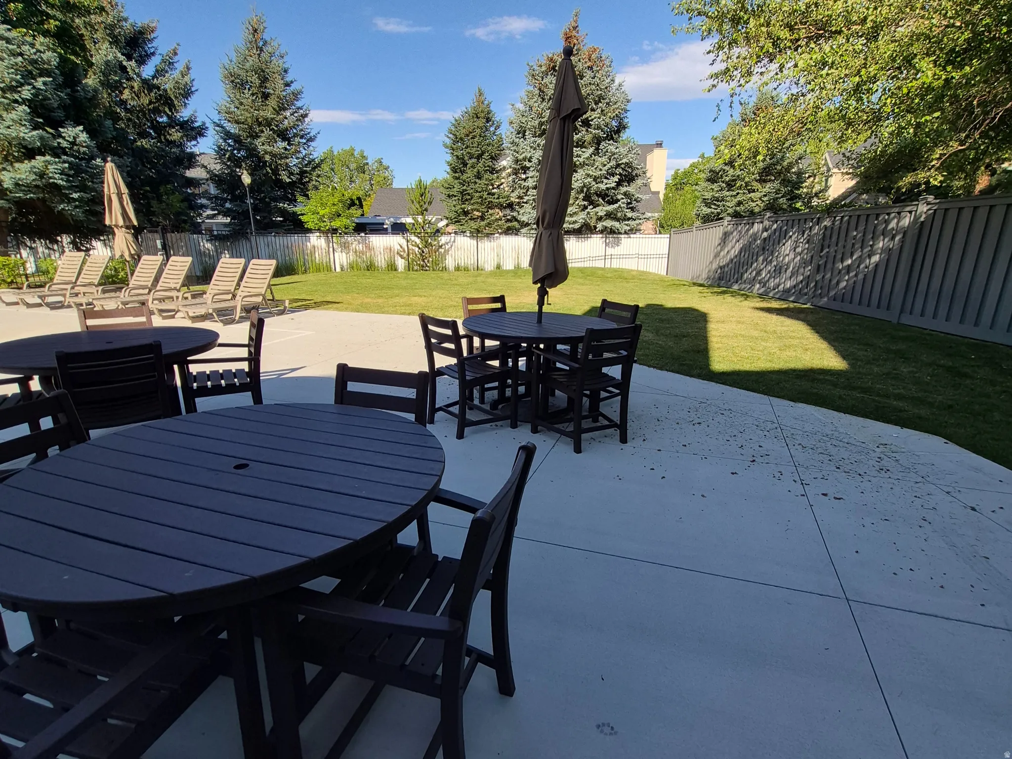 Expansive concrete patio with multiple seating areas at pool area