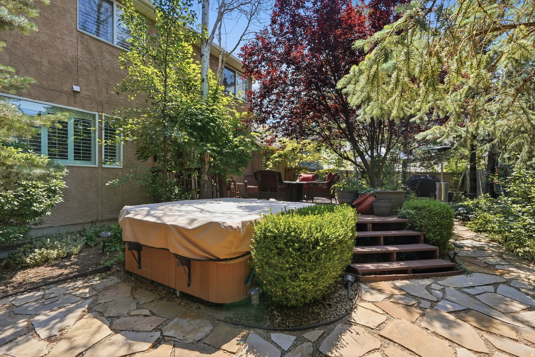 Private backyard with a flagstone patio, hot tub, and tiered deck