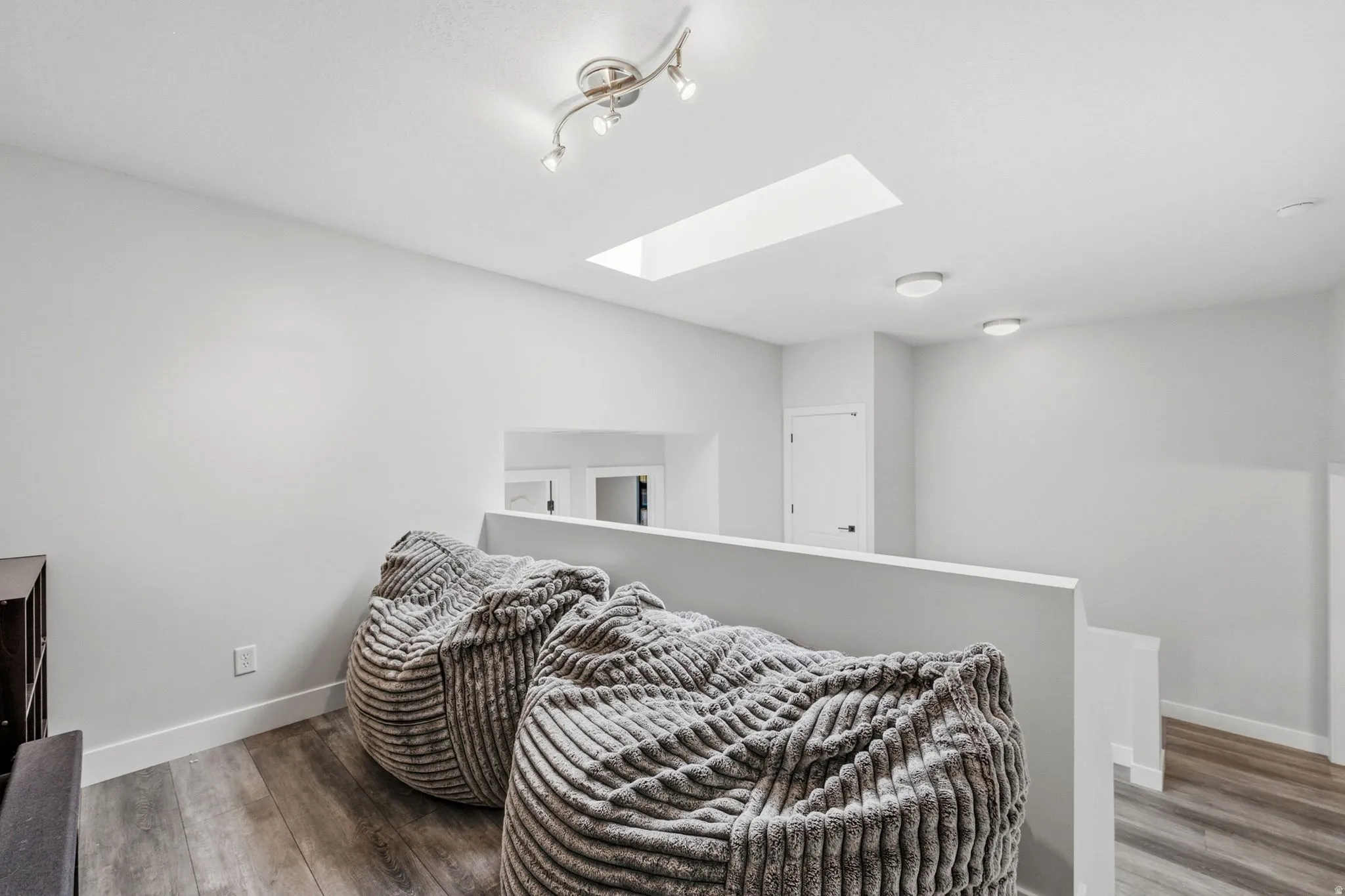 Loft space with wood-finish flooring, a skylight, and recessed lighting