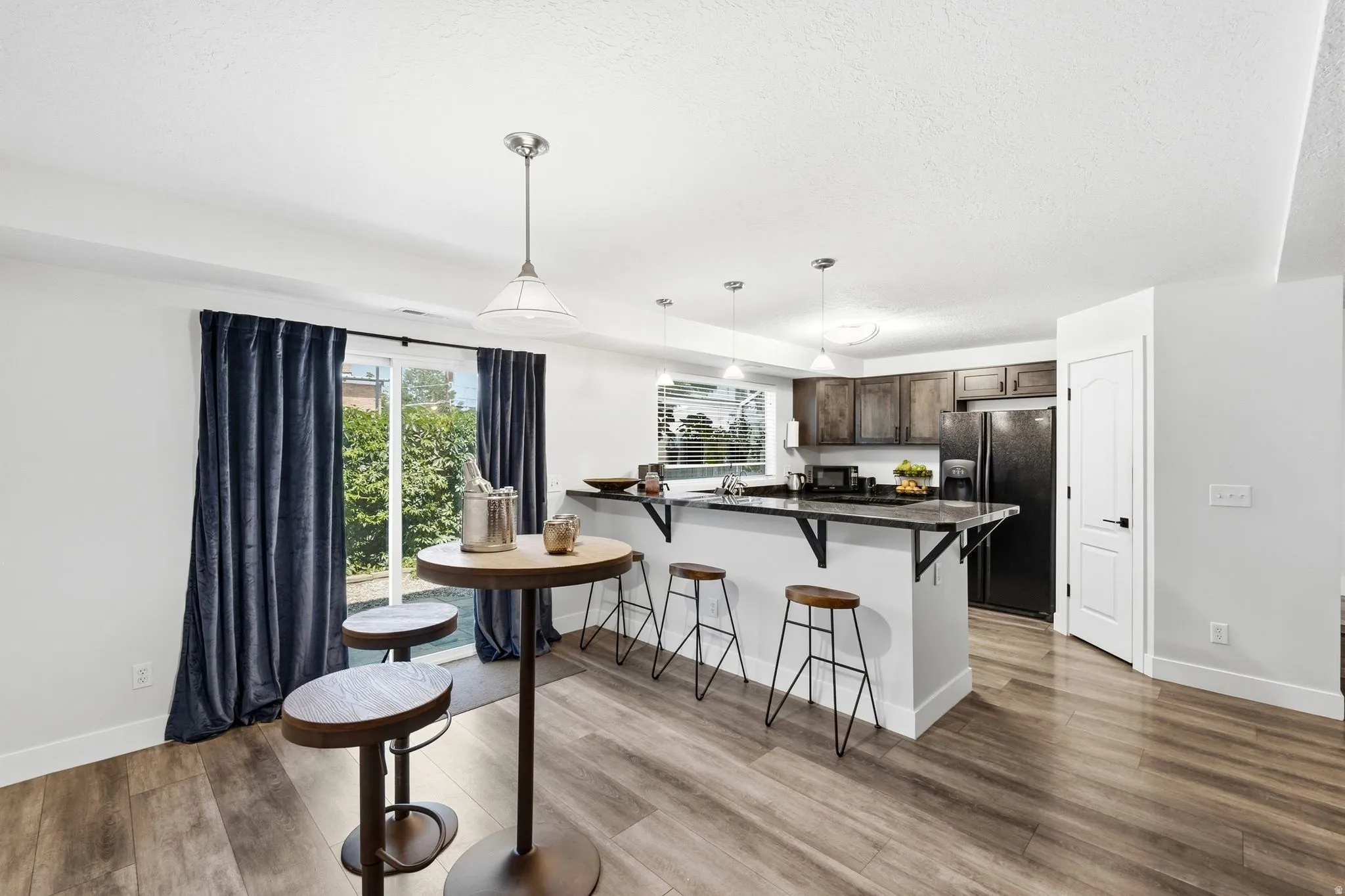 Kitchen with wood-finish flooring, dark cabinetry, and black appliances