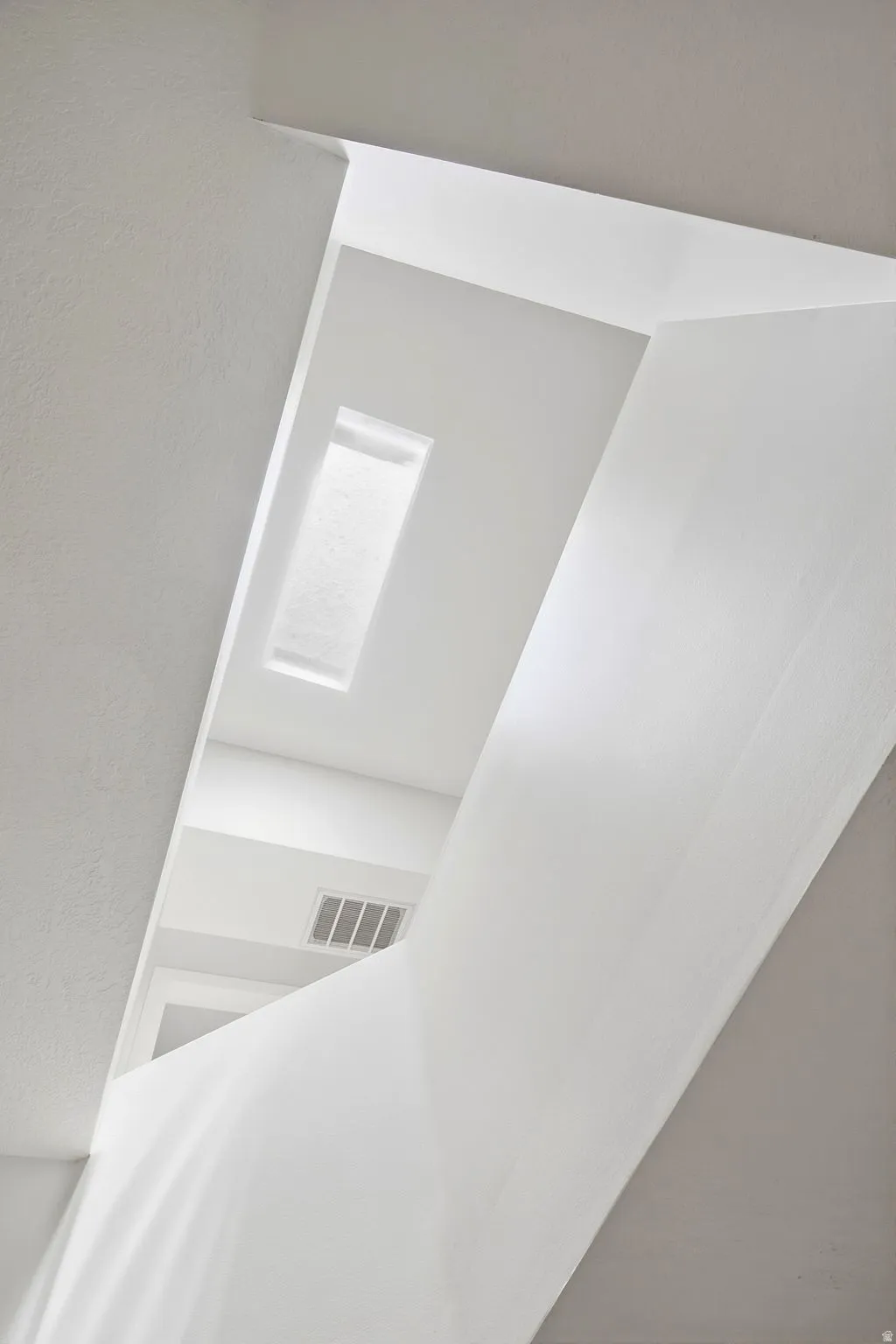 Architectural ceiling details with a skylight, white walls, and a visible air vent