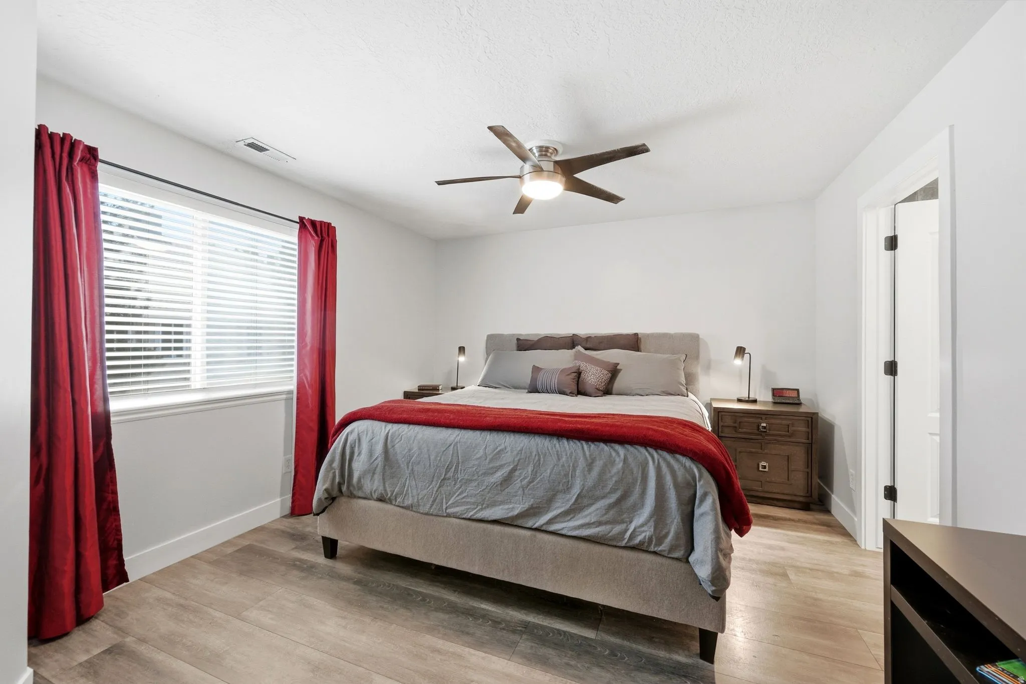 Bedroom featuring wood-finish flooring, a ceiling fan with integrated lighting, a window with blinds, and white trim
