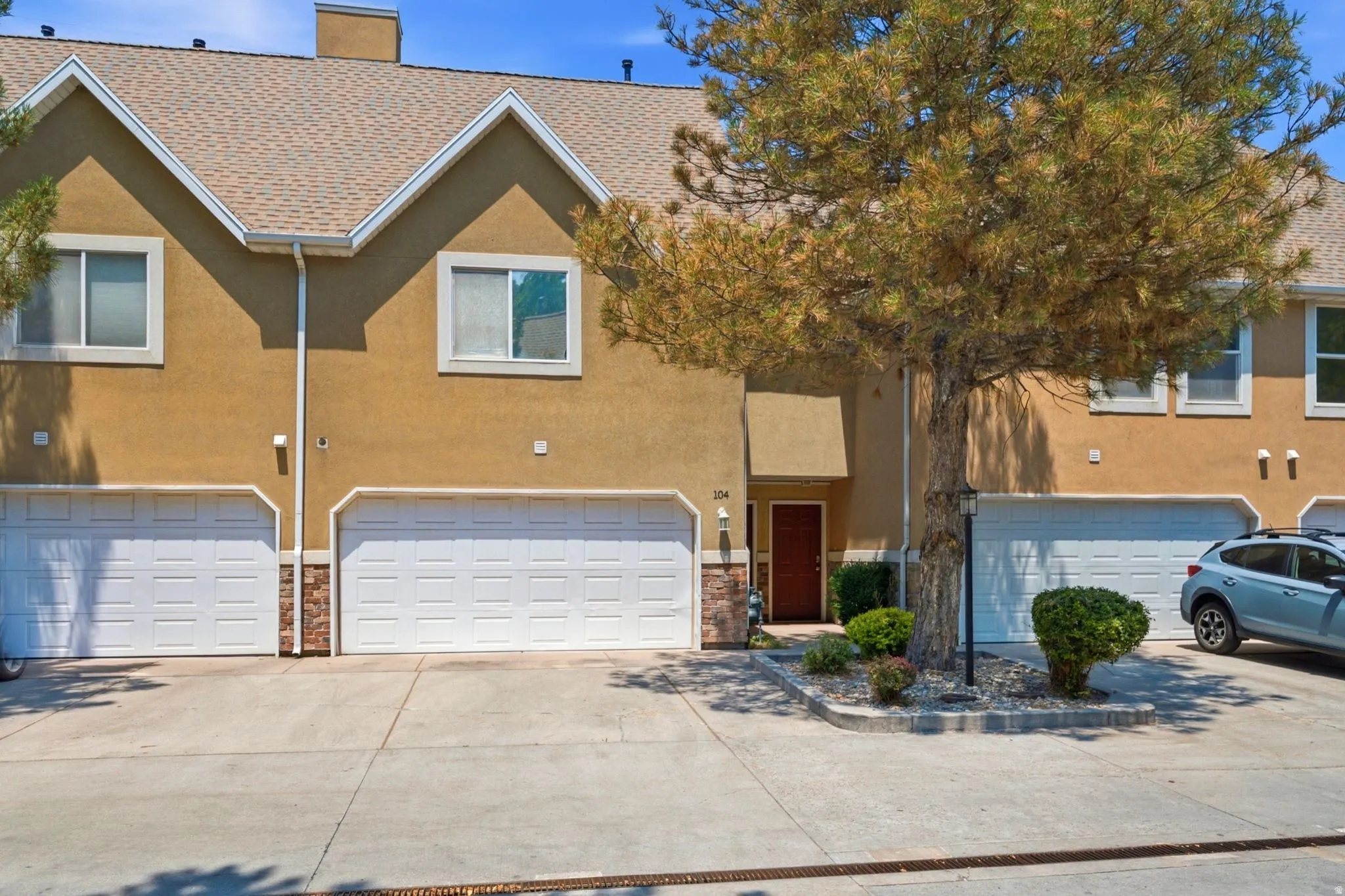 Multi-level townhome exterior featuring an attached two-car garage, stucco siding, and a gabled roofline