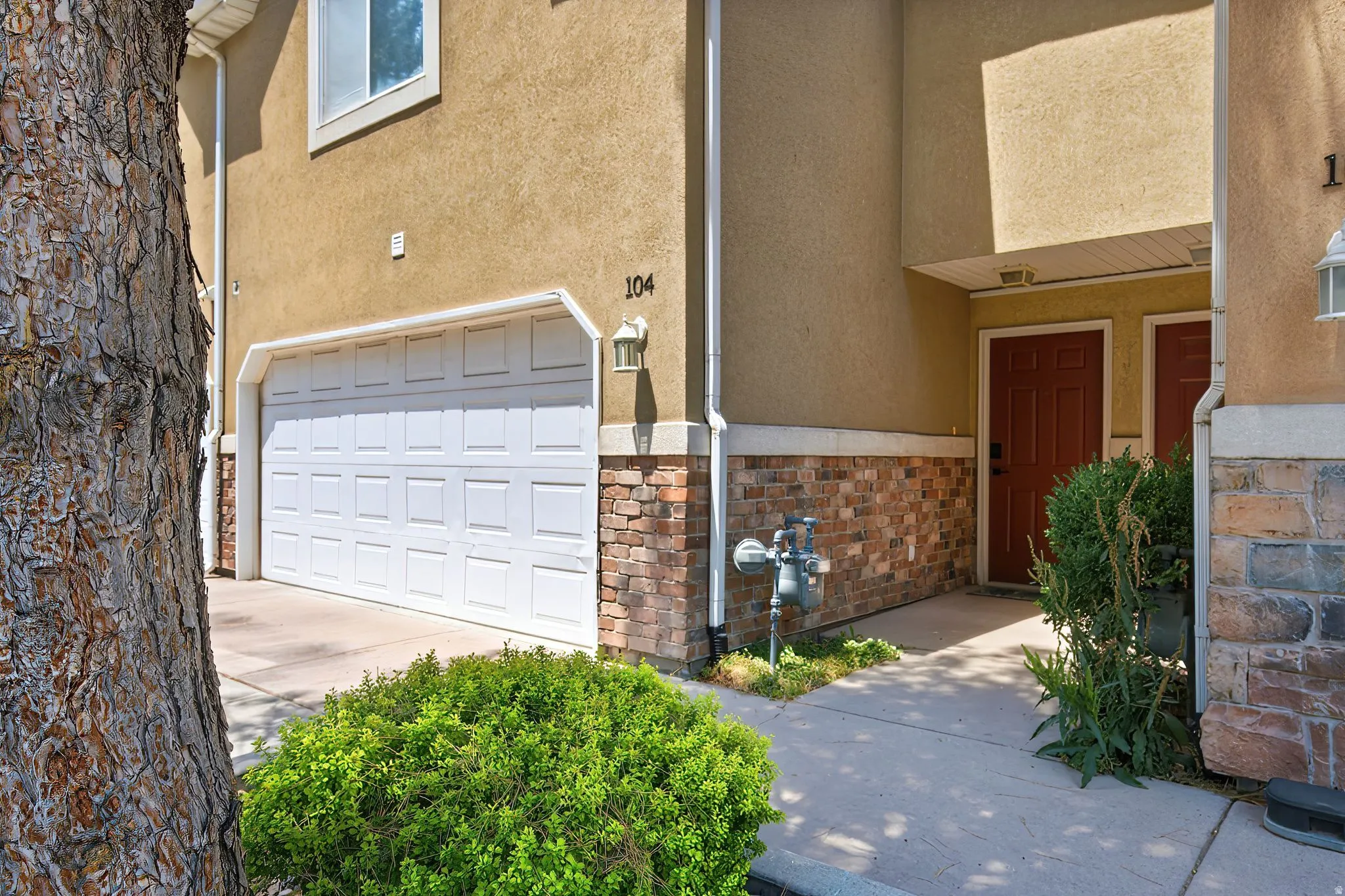 Exterior featuring a white paneled garage door, stucco siding, and stone veneer accents