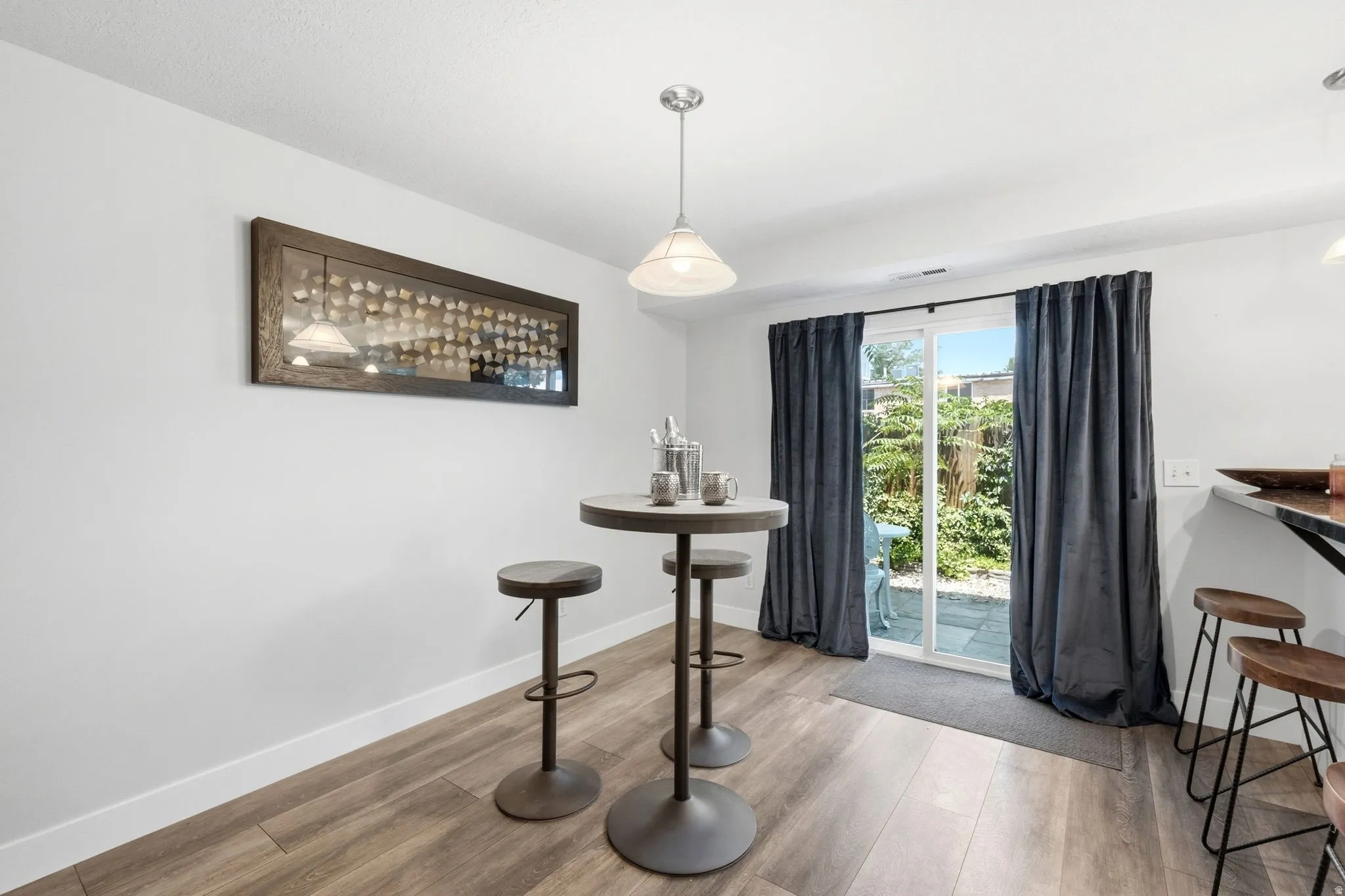 Interior space featuring wood-finish flooring, white walls, and a recessed ceiling with a pendant light fixture