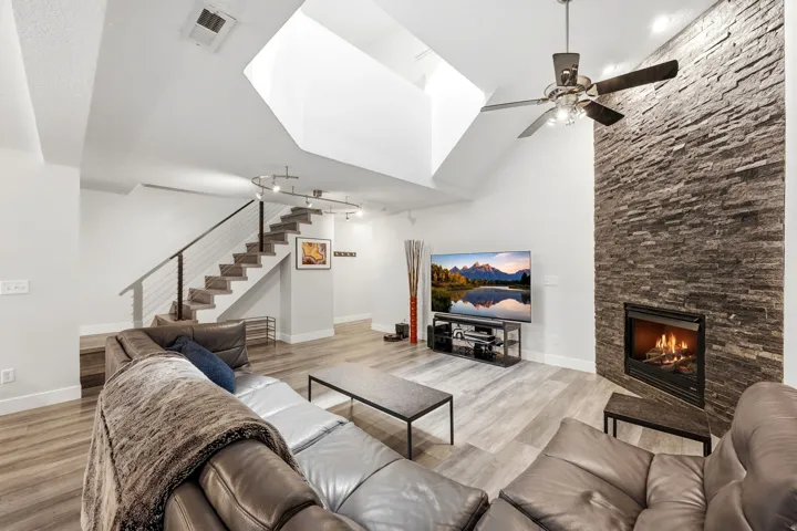 Spacious living area featuring a stacked stone fireplace with a black surround, vaulted ceilings, and recessed lighting