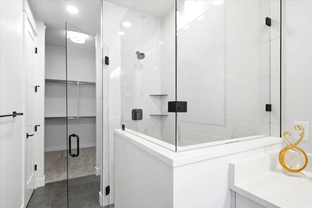 Glass-enclosed shower with matte black hardware and integrated shelving