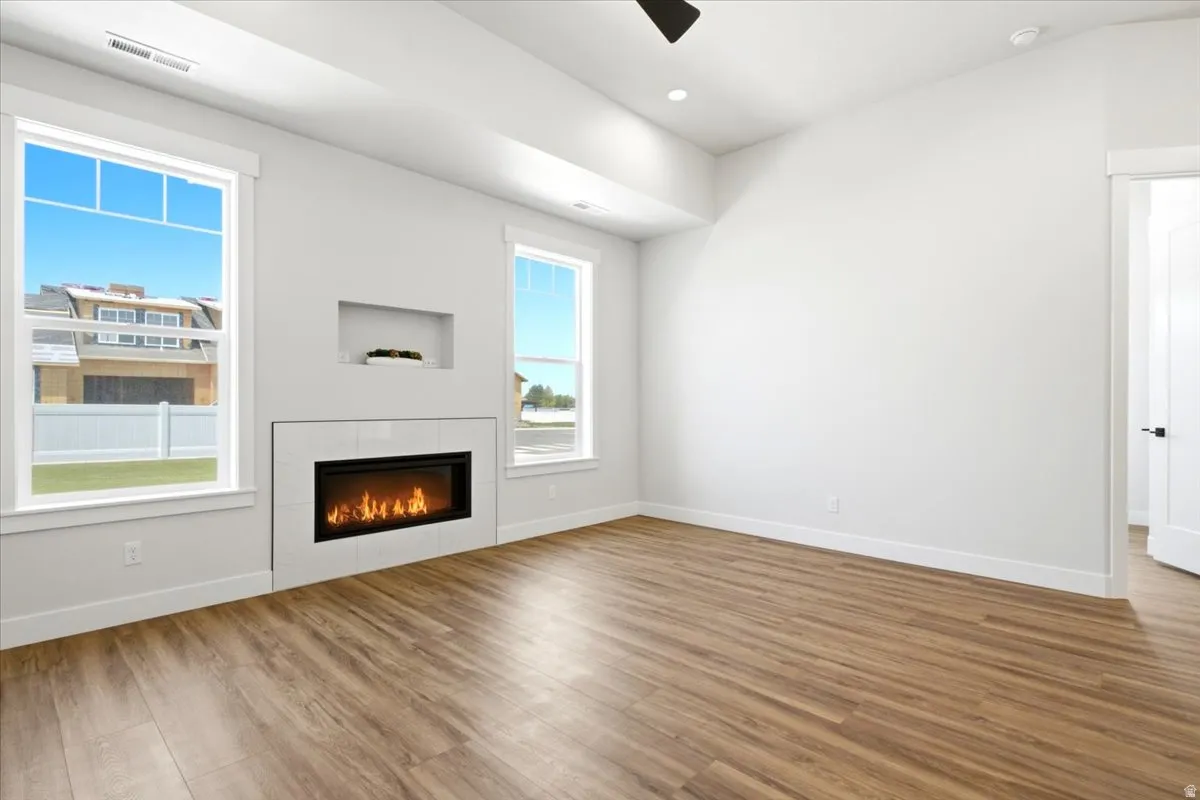 Modern living space featuring wood-finish flooring, a wall-mounted electric fireplace with a tiled surround, and an integrated wall niche