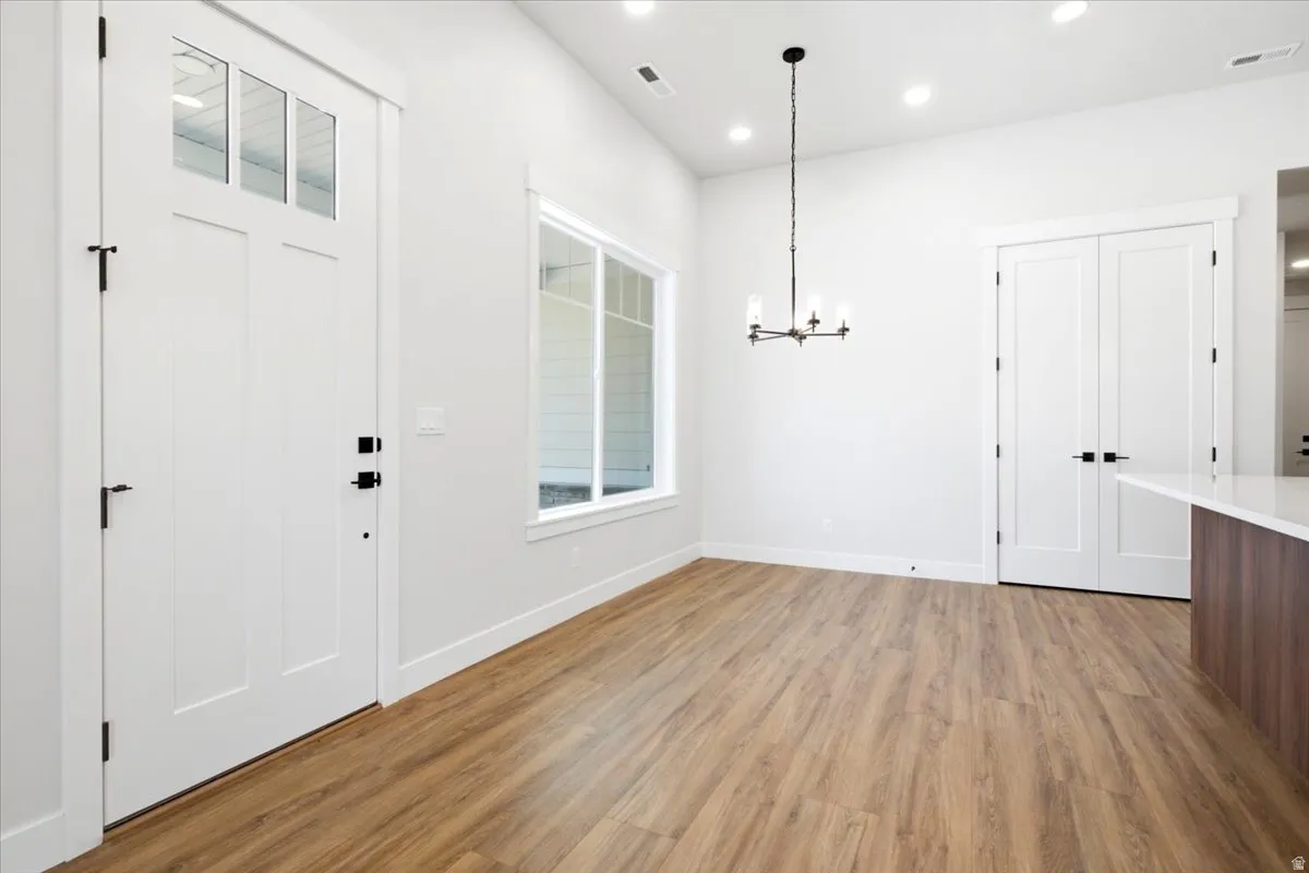 Entryway and interior space featuring wood-finish flooring, white trim, and a white paneled door with upper glass inserts