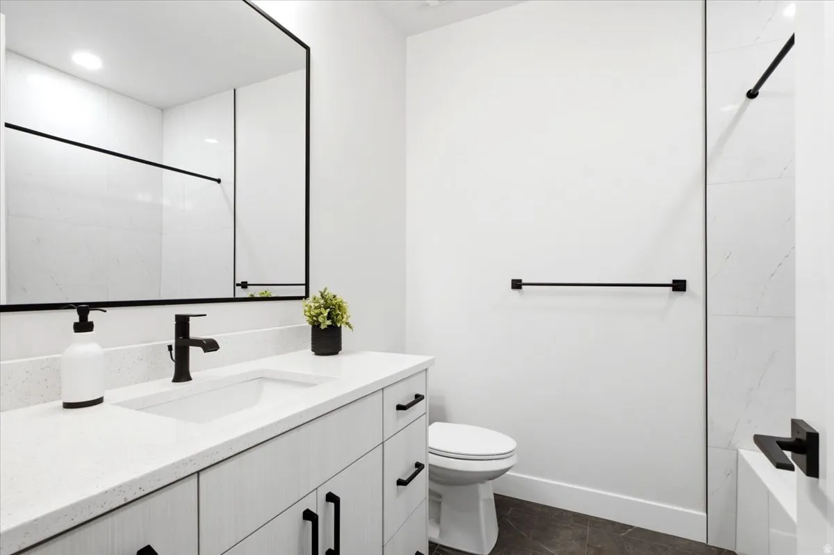 Contemporary bathroom featuring a light wood-finish vanity with quartz countertop, integrated rectangular sink, and matte black hardware