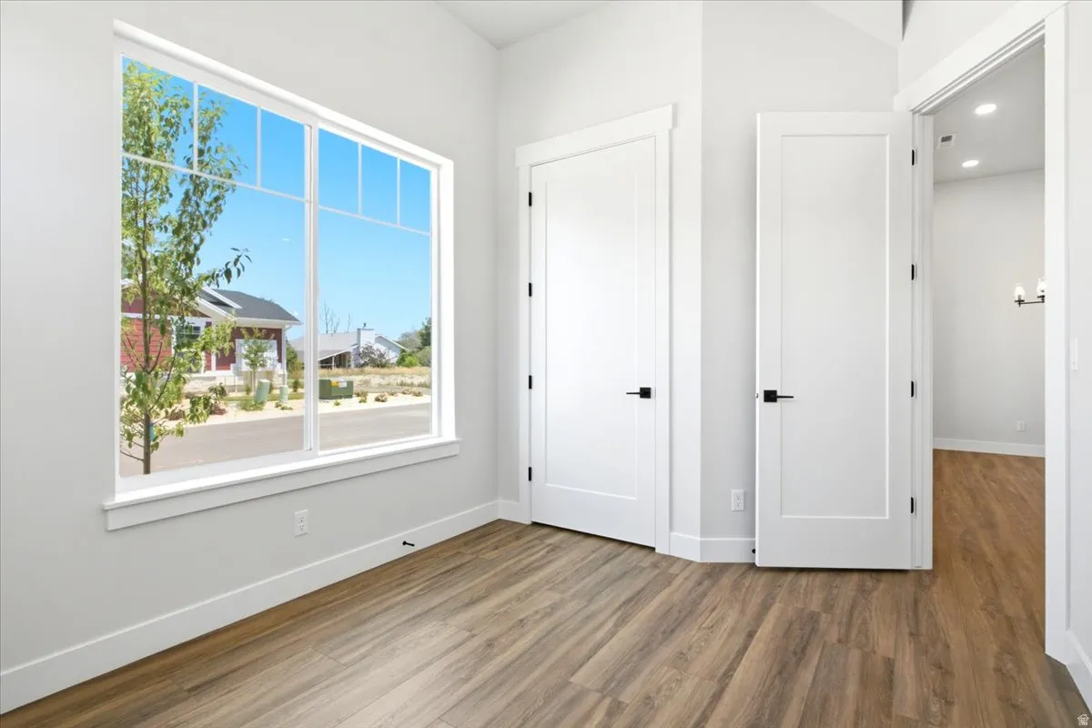 Bright interior space featuring a large multipane window, wood-finish flooring, and white trim