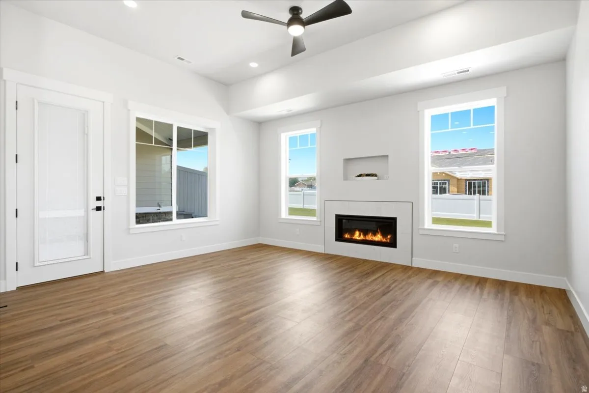 Living area featuring wood-finish flooring, a contemporary electric fireplace with a white surround, and recessed wall shelving