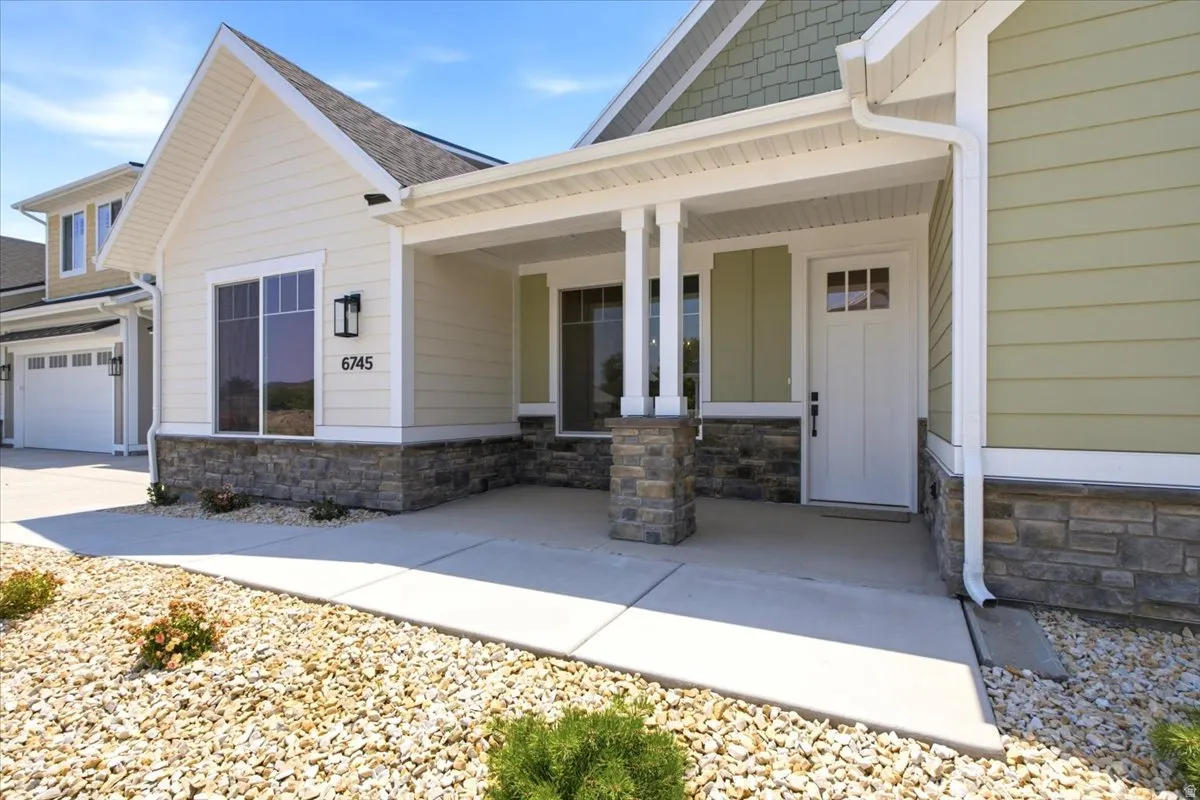 Inviting front entry featuring a covered porch, stone veneer accents, and a panel door with upper glass inserts