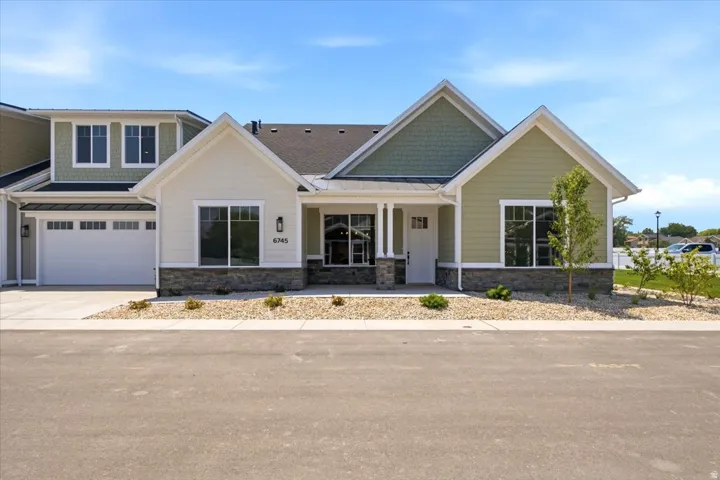 Contemporary ranch-style exterior with a two-car garage, stone façade accents, and a covered entry