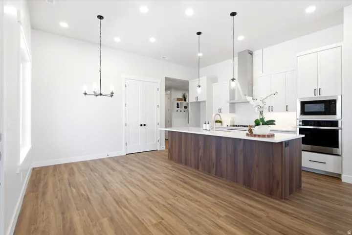 Open-concept kitchen and dining area featuring wood-finish flooring, white walls, and recessed lighting