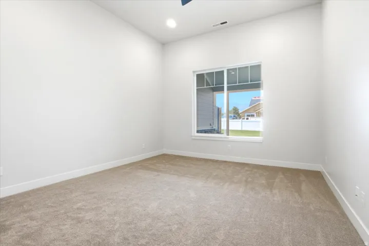 Spacious room with light neutral carpeting, white walls, and a large window providing ample natural light