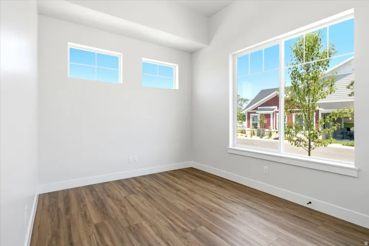 Spacious room featuring wood-finish flooring, white baseboards, and bright white walls