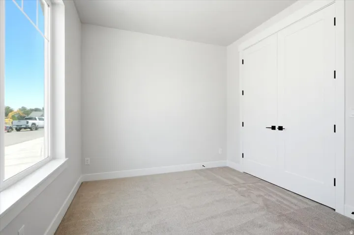 Neutral tone wall paint with white trim, light-colored carpet, and a large window with white framing