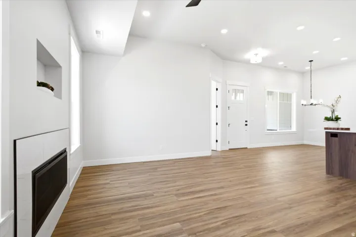 Spacious open-concept interior featuring wood-finish flooring, recessed lighting, and a modern fireplace with a tiled surround