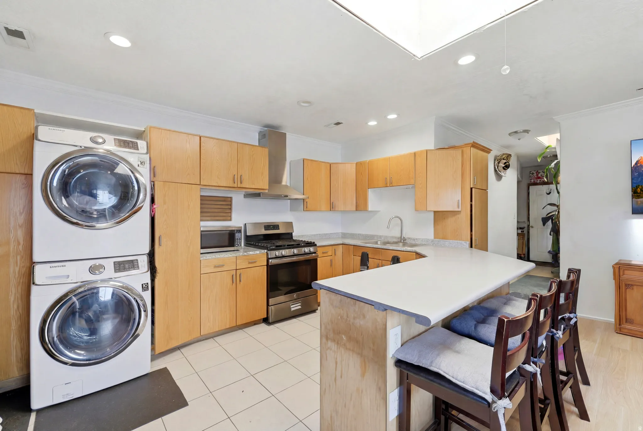 Modern kitchen featuring light wood cabinetry, white countertops, and stainless steel appliances