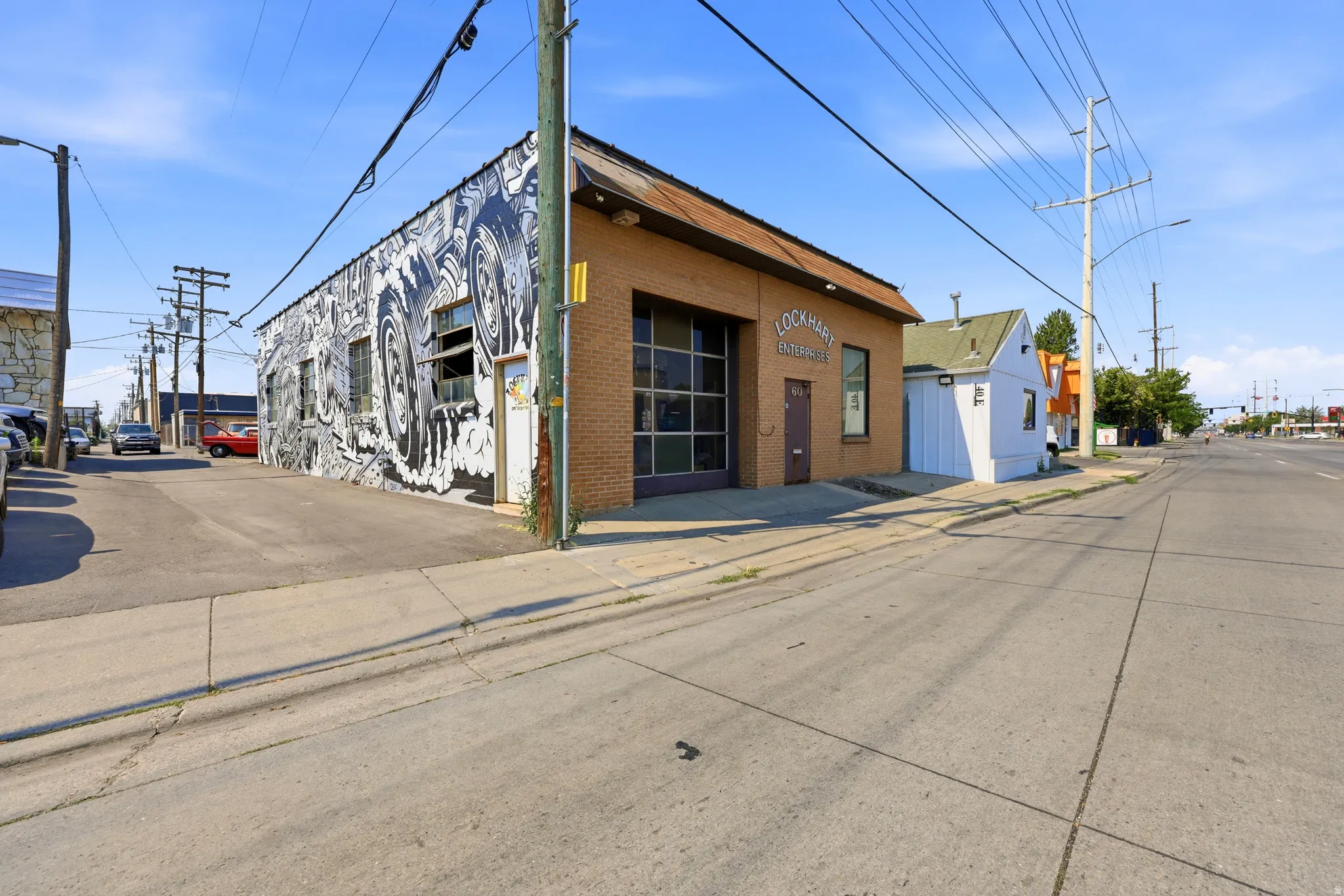 Brick commercial building featuring a large glass garage door, brown entry door, and a street-facing mural