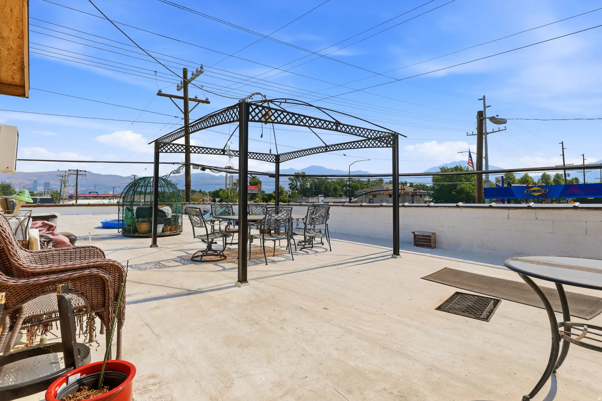 Spacious rooftop patio featuring a metal gazebo, concrete flooring, and a white perimeter wall