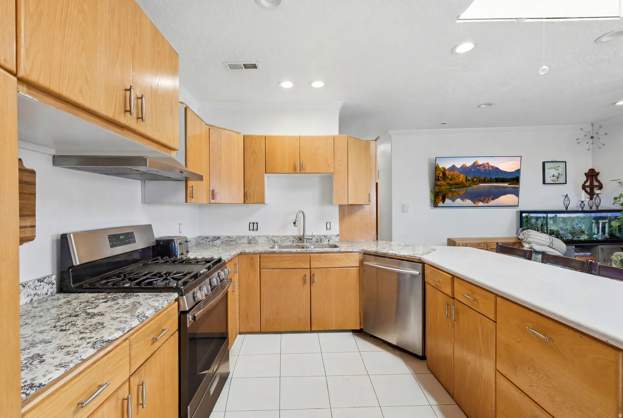 Kitchen featuring natural wood cabinetry and light-toned granite countertops