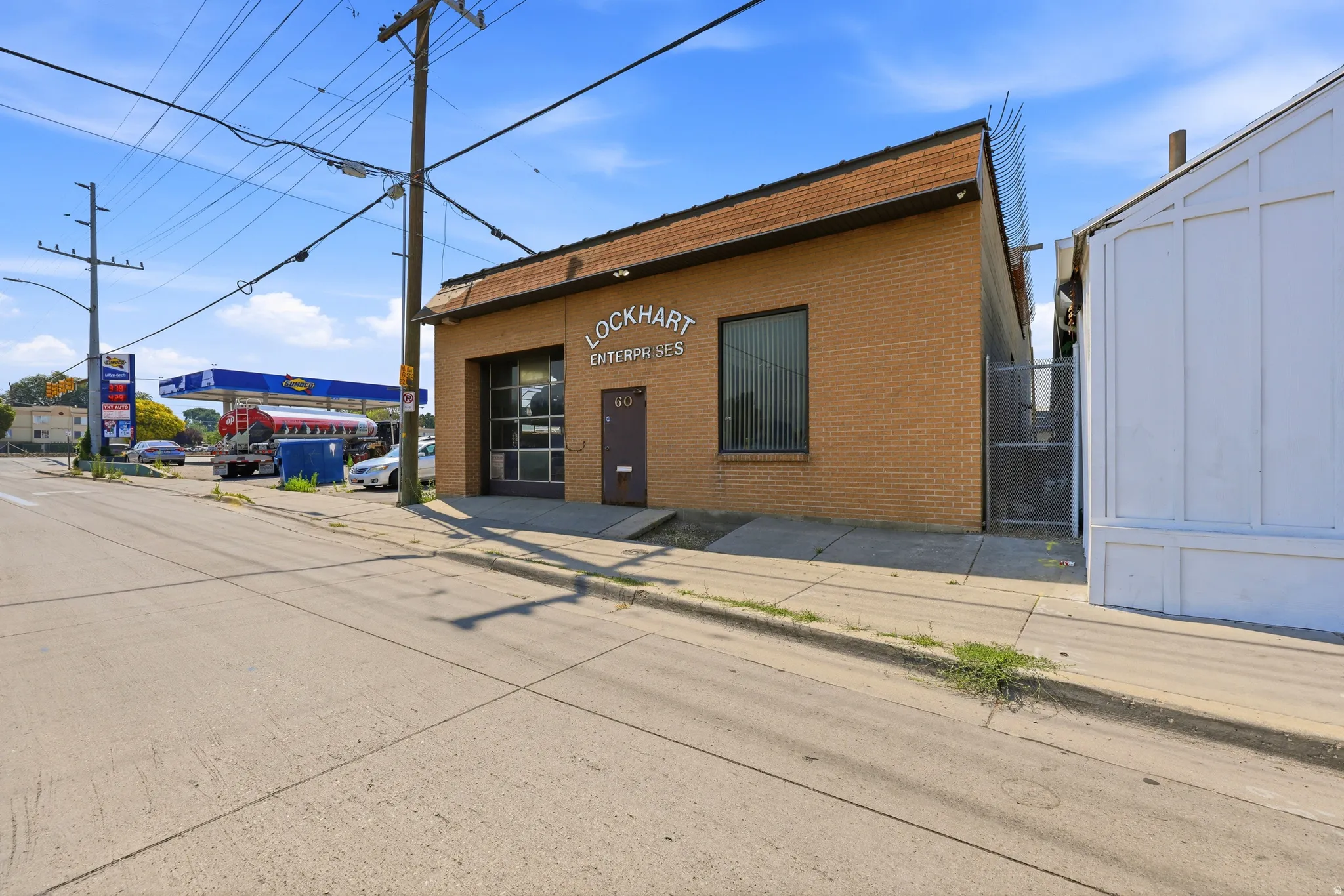 Brick commercial building featuring a large roll-up door, prominent signage, and a pedestrian entrance