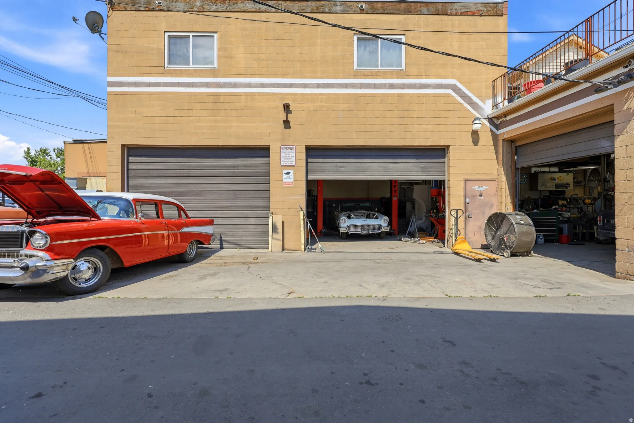 Commercial structure featuring multiple roll-up doors, an upper-level window, and an exterior balcony