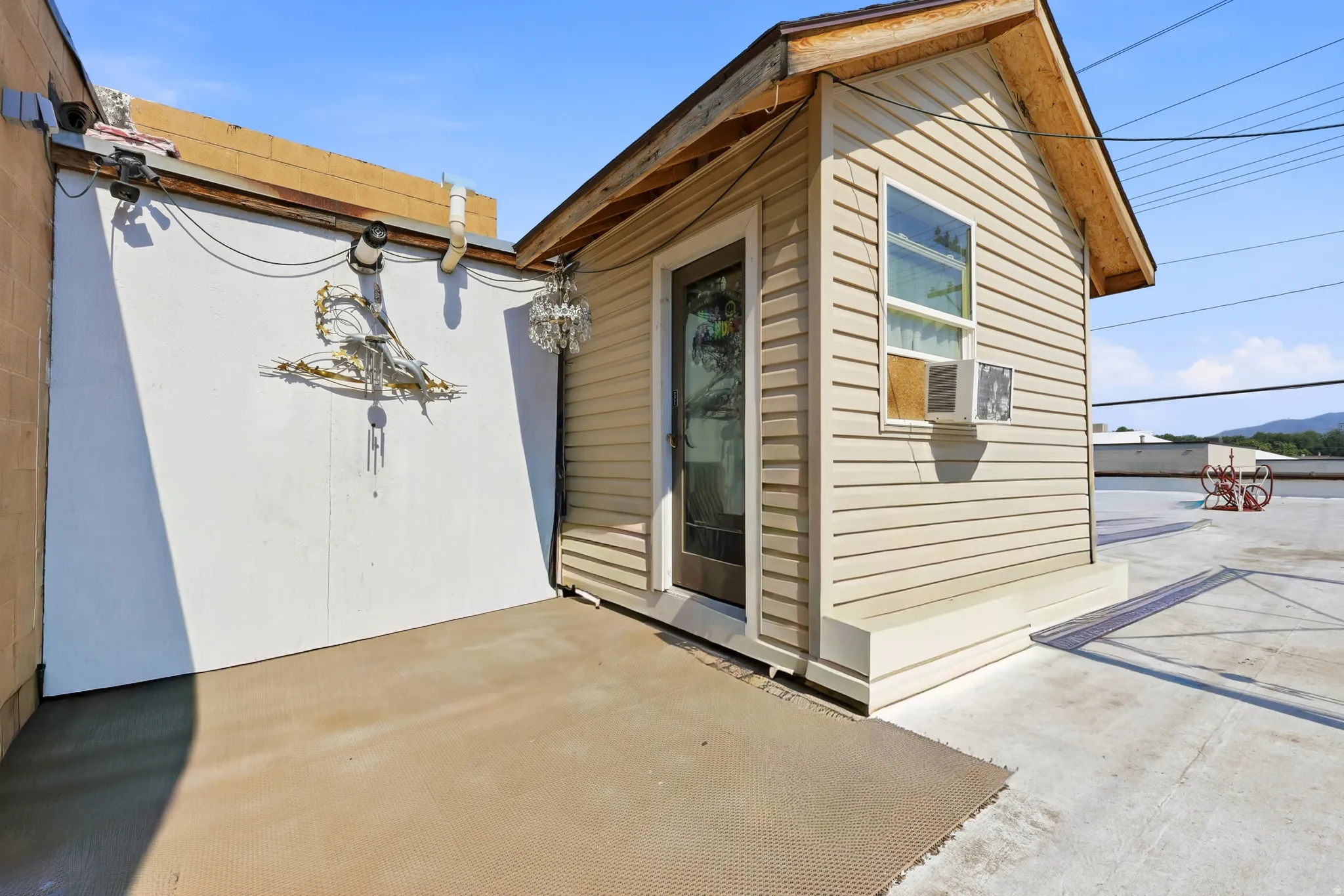 Attached structure with light beige siding and a dark-framed glass door