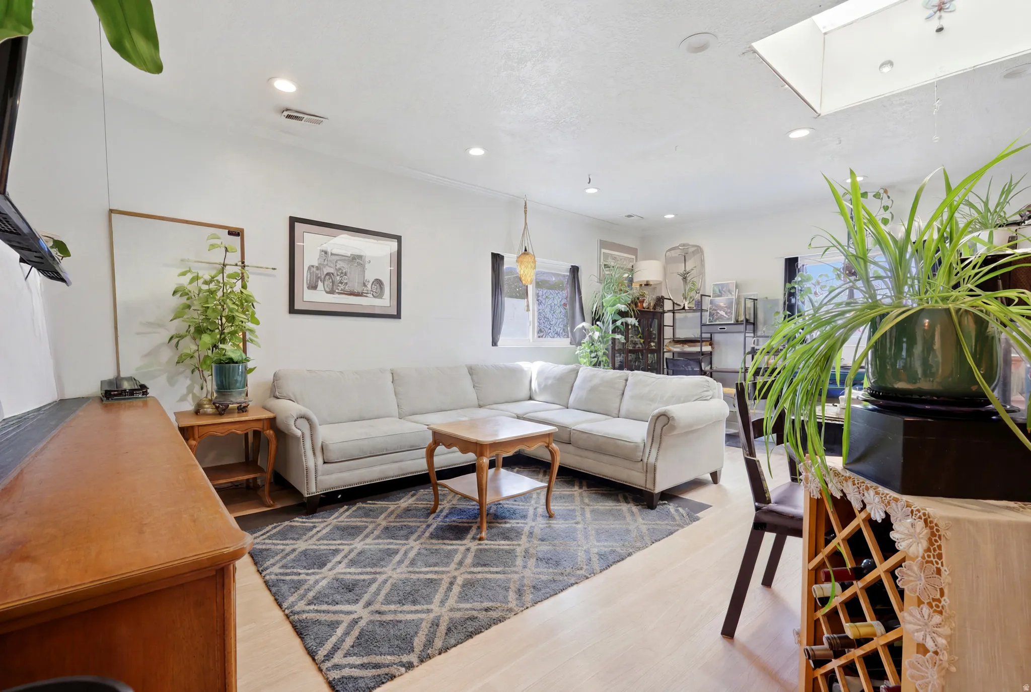 Living area with light-toned wood-finish flooring, recessed lighting, and a skylight
