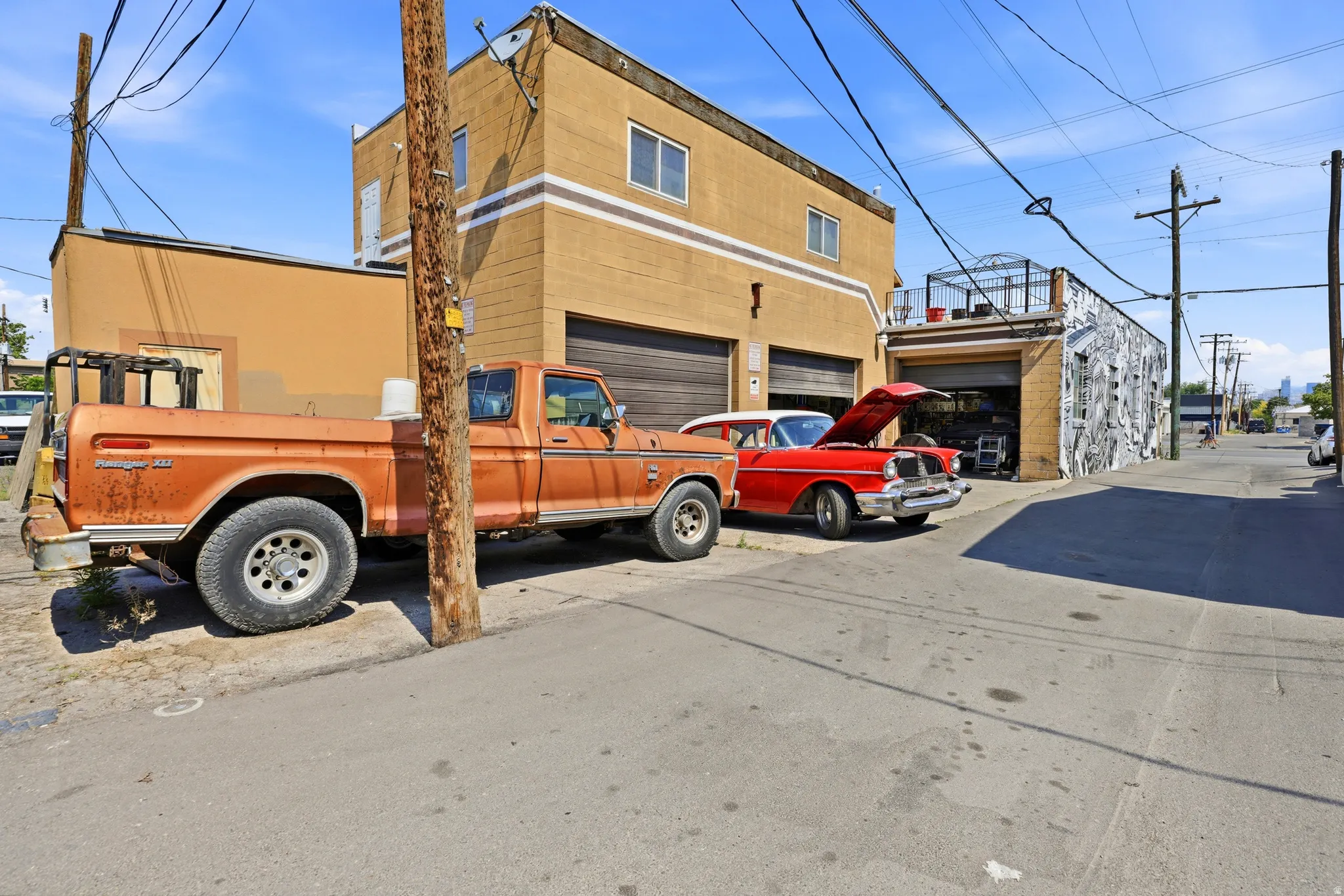 Industrial-style building featuring a two-story tan facade with striped detailing, two garage doors, and multiple windows