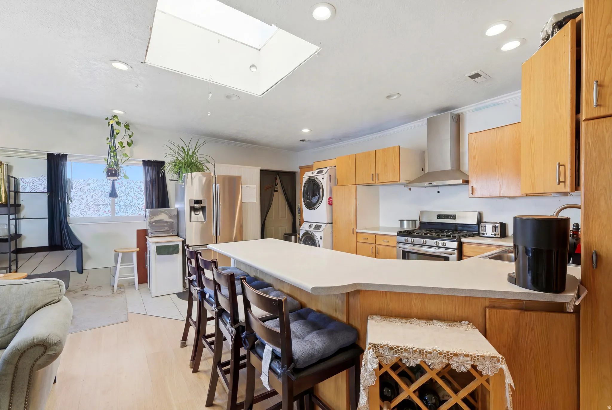 Open-concept kitchen featuring light wood cabinetry and a stainless steel appliance suite