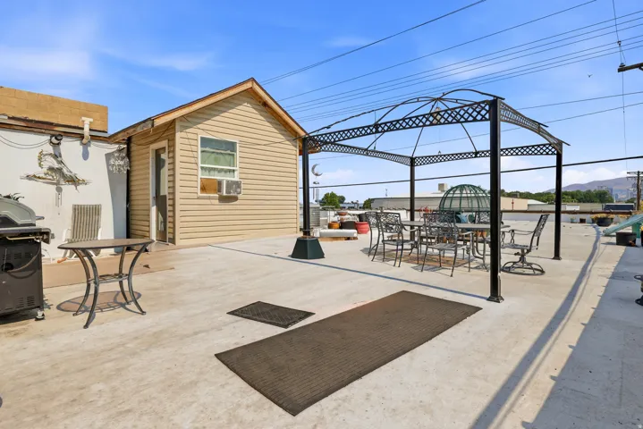 Rooftop patio featuring an outdoor gazebo structure, a beige siding shed with a window, and a concrete surface