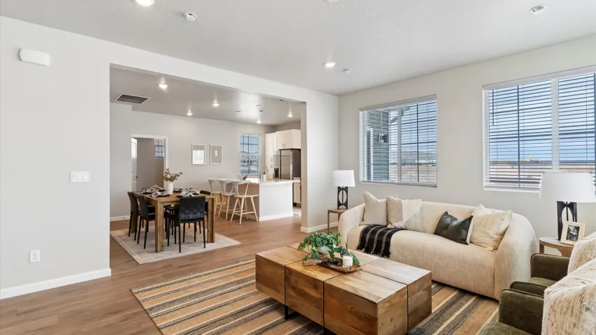 Open-concept living area featuring wood-finish flooring, recessed lighting, and large windows with blinds