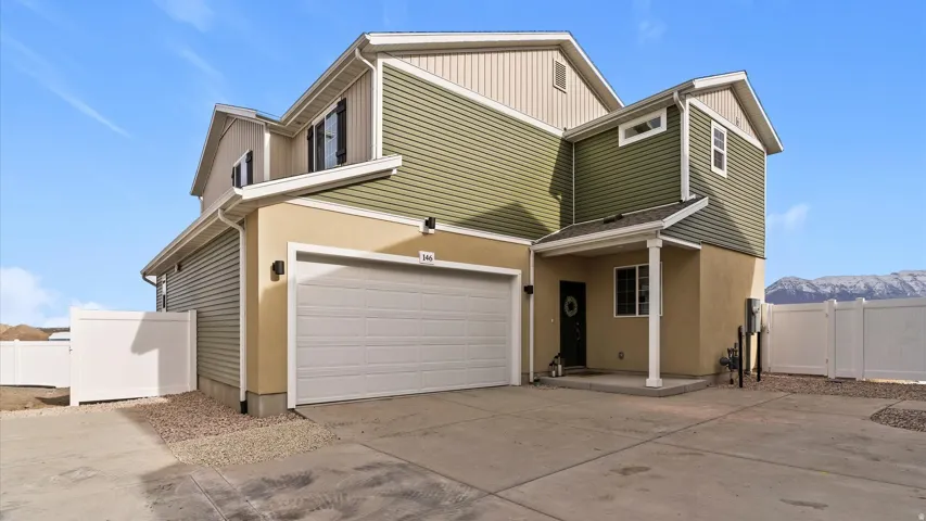 Multi-story exterior with a two-car garage, stucco and horizontal siding, a covered entry, and a gravel perimeter